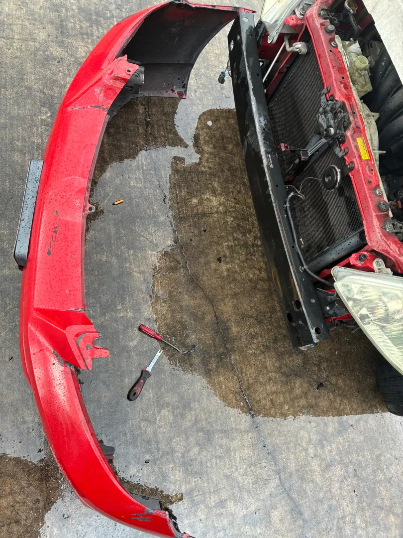 Bumper cover on the ground, radiator support and headlight exposed behind it — Riverside, CA
