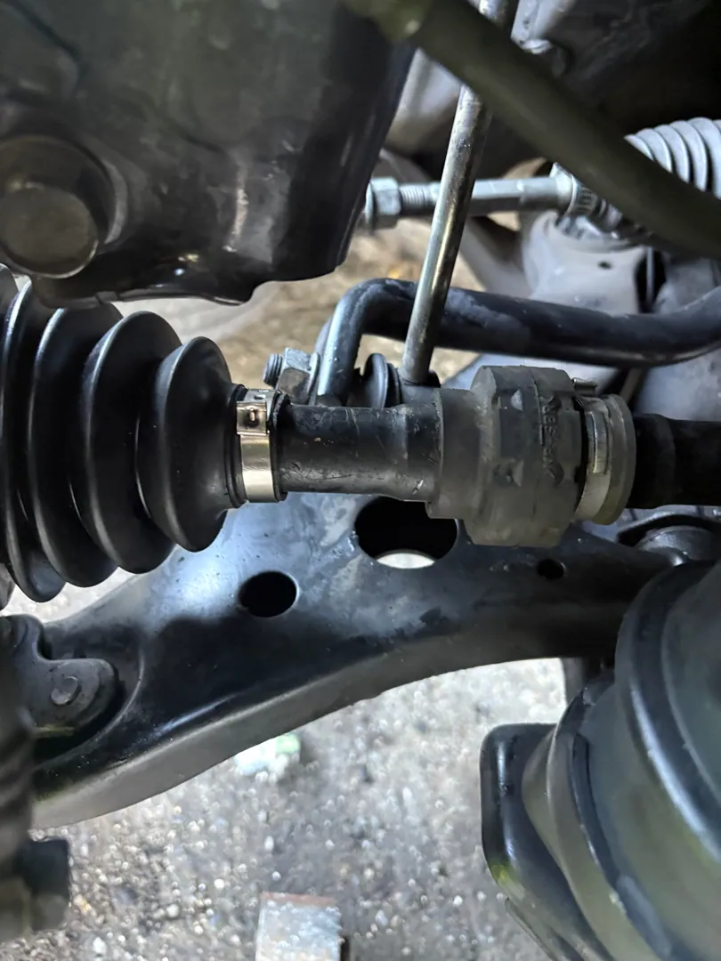 Fresh CV boot clamped on the inner joint, control arm and ball joint visible behind it — San Jacinto, CA